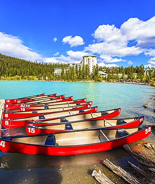 Red canoes for tourists are moored to the coast. Rocky Mountains. Glacial Lake Louise - the lake with azure water is surrounded by forests. The concept of ecological, active and photo tourism