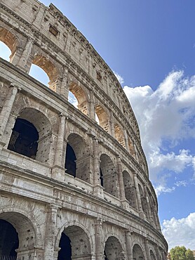 Partial view of the Colosseum under a blue sky with clouds, Rome, Italy