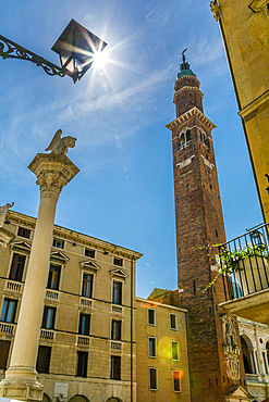 Sun peeking from street lamp and clock tower of Palladian Basilica in Piazza Signori, Vicenza, Veneto, Italy, Europe