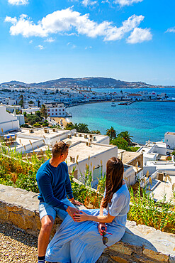 Young couple with elevated view of flour mills and town, Mykonos Town, Mykonos, Cyclades Islands, Greek Islands, Aegean Sea, Greece, Europe