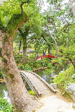 View of red footbridge over Takueichi Pond in Shukkeien Garden, Kaminoboricho, Naka Ward, Hiroshima, Japan, Asia