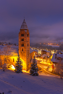 View of Church of Saint Pantalon and the snow covered town centre and mountainous background in winter at dusk, Courmayeur, Aosta Valley, Italy, Europe