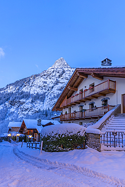 View of chalets and snow covered mountains in Courmayeur before dawn during winter, Courmayeur, Aosta Valley, Italy, Europe