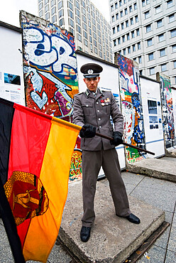 East German guard with former GDR flag in front of remains of the Berlin Wall, Potsdamer Platz, Berlin, Germany, Europe