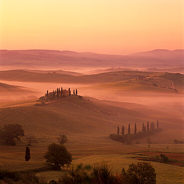 Tuscan farmhouse with cypress trees in misty landscape at sunrise, San Quirico d'Orcia, Siena Province, Tuscany, Italy, Europe