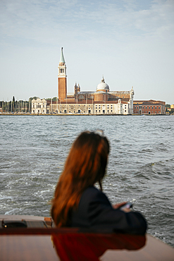 Woman on boat with San Giorgio Maggiore in the background, San Marco, Venice, Italy