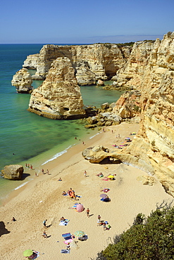 Overview of tourists on beach, sandstone cliffs and seastacks at Praia da Marinha, near Carvoeiro, Algarve, Portugal, Europe