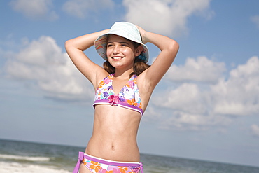 Portrait of girl on beach with hands behind head