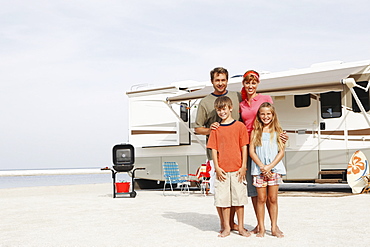 Family posing on beach in front of motor home