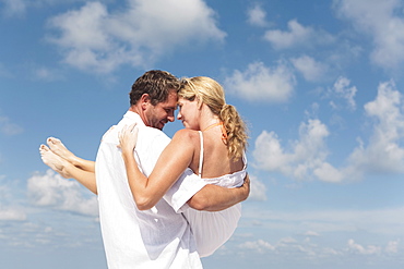 Man carrying girlfriend on beach