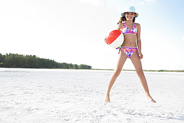 Girl jumping on beach with beach ball 