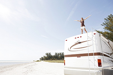 Young woman standing on top of motor home