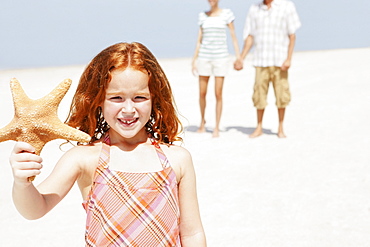 Girl holding up starfish on beach