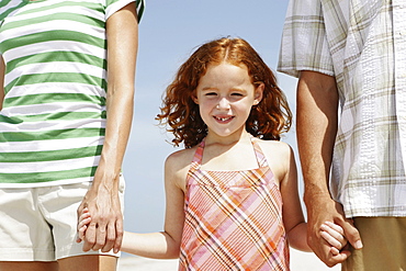 Girl holding hands with mother and father