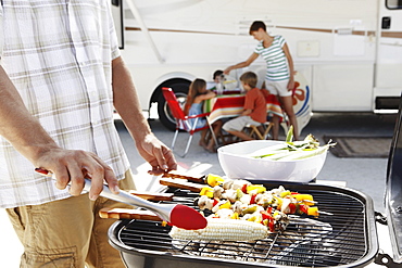 Man grilling dinner for family on beach