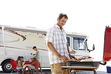 Man grilling dinner for family on beach