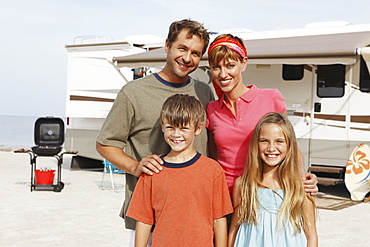 Family posing by motor home on beach