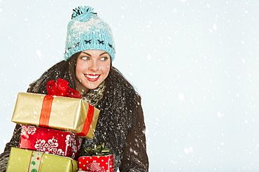 Studio portrait of woman in winter clothing carrying presents