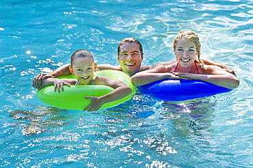 Girl (10-11) with parents in swimming pool