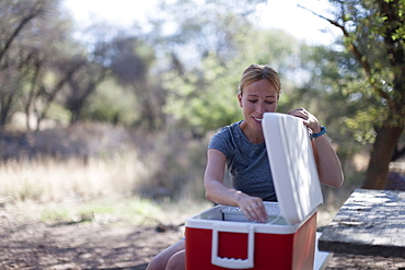 Smiling woman opening cooler in park, Davis Mountains State Park, Texas, USA