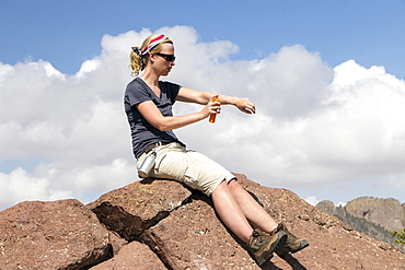 Woman sitting on rock and applying suntan lotion, Big Bend National Park, Texas, USA