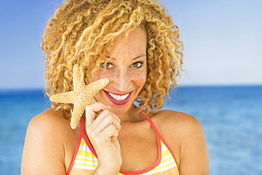 Portrait of young woman holding starfish
