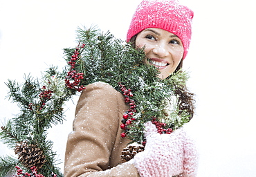 Portrait of woman in winter clothes carrying wreath