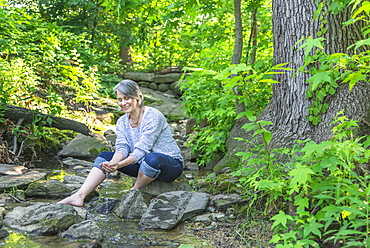 Senior woman sitting by stream, Central Park, New York City