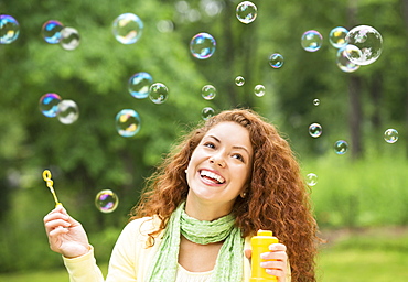 Young woman blowing bubbles in park