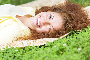 Portrait of young woman lying on grass in park