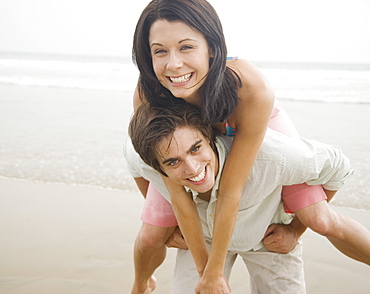 Man giving woman piggyback ride at beach