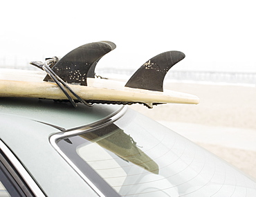 Close up of surfboard on top of car at beach