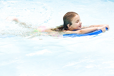 Girl using kickboard in swimming pool