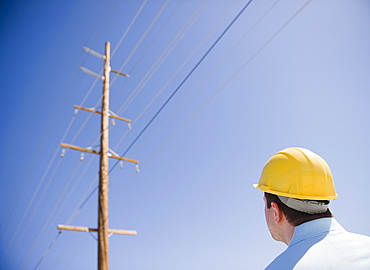 Man in hard hat looking at telephone pole