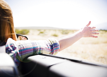 USA, California, Palm Springs, Coachella Valley, San Gorgonio Pass, Woman stretching arm outside convertible car