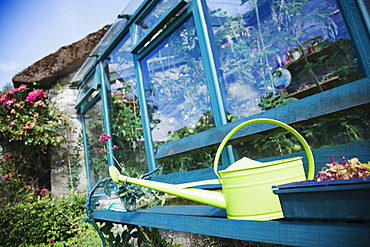 Ireland, County Westmeath, Watering can in front of greenhouse