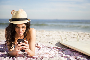 Woman using cell phone on beach, Rockaway Beach, New York