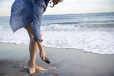 Woman collecting seashells on beach, Rockaway Beach, New York