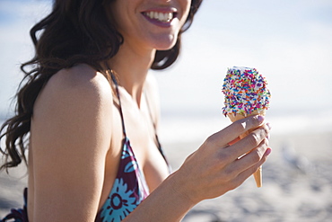 Woman eating icecream on beach, Rockaway Beach, New York