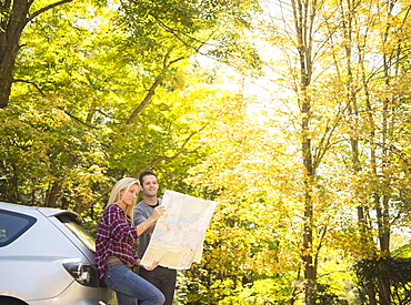 Couple leaning against car and reading map, Newtown, Connecticut