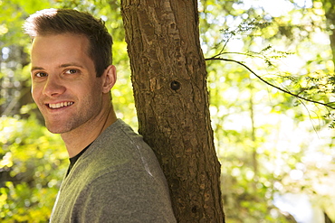 Portrait of young man leaning against tree trunk, Newtown, Connecticut