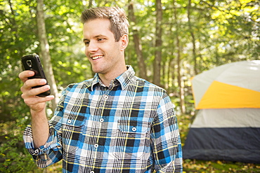 Man using cell phone in forest, Newtown, Connecticut