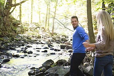 Couple walking by stream in forest, Newtown, Connecticut