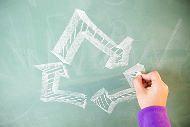 View of arrows on blackboard and girl's hand