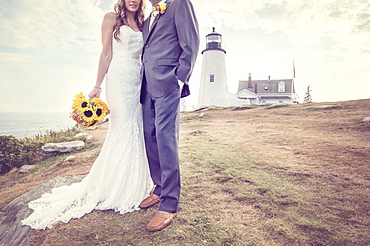 Low section of married couple, lighthouse in background, USA, Maine, Bristol 