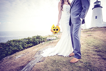 Low section of married couple, lighthouse in background, USA, Maine, Bristol 