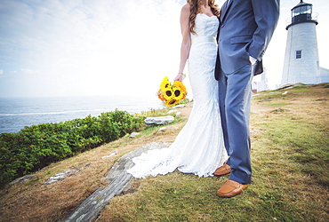 Low section of married couple, lighthouse in background, USA, Maine, Bristol 