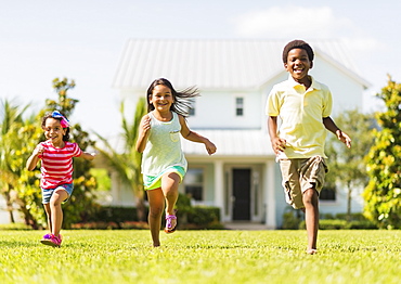 Girls( 4-5, 8-9) and boy (6-7) playing on front yard, Jupiter, Florida