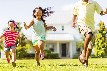 Girls( 4-5, 8-9) and boy (6-7) playing on front yard, Jupiter, Florida