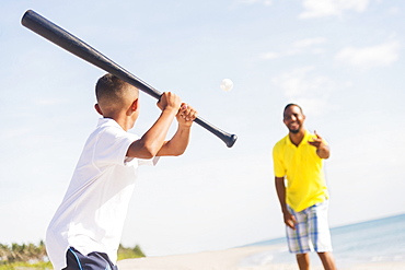 Father and son (10-11) playing baseball on beach, Jupiter, Florida